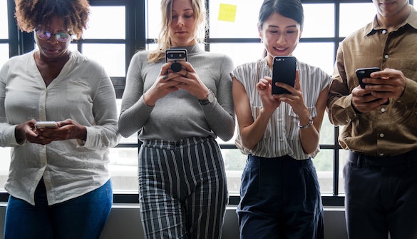 Drei Frauen und 1 Mann beim spielen am Handy